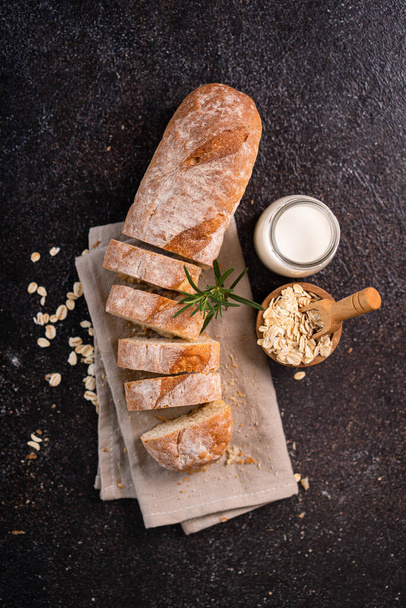 Sliced baguette bread on wooden coaster and rustic background. Artisan Sourdough bread. - Foto, Imagen