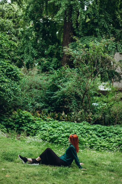 Femme caucasienne est assise sur l'herbe dans le jardin botanique Brera, une partie du complexe de l'Académie, Milan centre-ville, Italie, Se reposer, penser. Détente dans le parc en été. Espace de copie - Photo, image