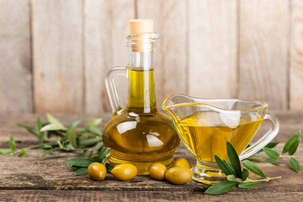 Olivenöl in einer Flasche auf braunem Hintergrund. Ölflasche mit Zweigen und Früchten von Oliven. Platz für Text. Kopierraum. Speiseöl und Salatdressing. - Foto, Bild