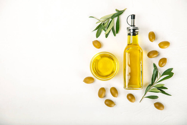Oliiviöljy valkoisella pohjalla olevassa pullossa. Öljypullo, jossa oksat ja hedelmät oliiveja. Tekstipaikka. Kopioi ruokaöljy ja salaatinkastike - Valokuva, kuva