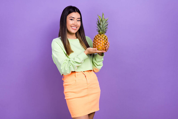 Photo of adorable nice girl dressed green sweatshirt holding pine apple empty space isolated violet color background. - Photo, Image
