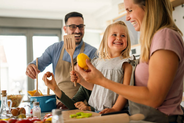 Happy family preparing healthy food together in kitchen - Foto, afbeelding