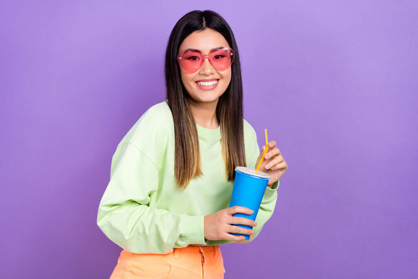 Photo of cheerful girlish good mood woman with dyed hairdo dressed green pullover hold soda cup isolated on purple color background. - Foto, imagen