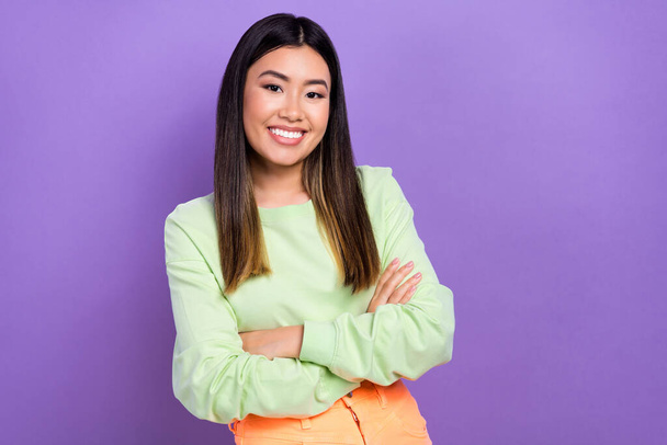 Photo of confident cheerful lady wear green sweatshirt arms crossed empty space isolated purple color background. - Photo, Image