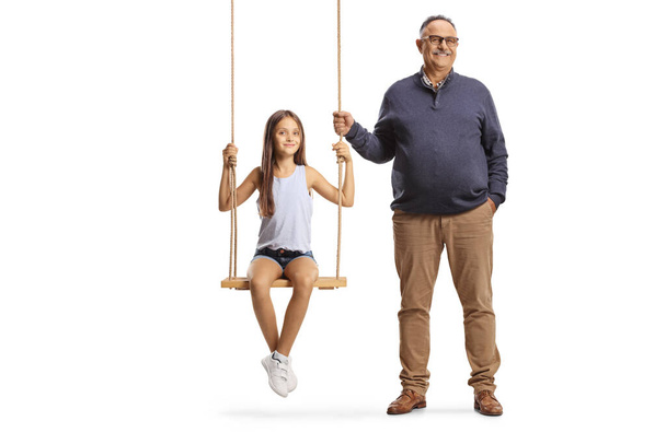 Mature man standing next to girl on a wooden swing isolated on white background - Zdjęcie, obraz