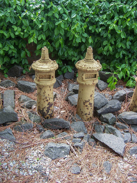 Δύο παλιές, σκουριασμένες μεταλλικές βαλβίδες με ξεφλούδισμα κίτρινου χρώματος και δείκτες που γράφουν SHUT ανάμεσα σε βράχους με θάμνους στο βάθος. - Φωτογραφία, εικόνα