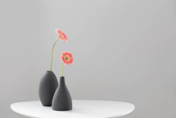 pink gerber in gray vases on white table on background gray wall - Photo, Image