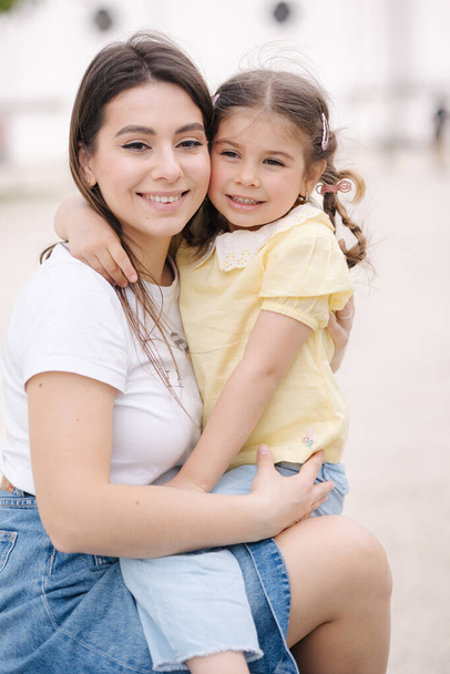 Cute girl hug her mom and have fun. Female with daughter outdoor. High quality photo - Photo, Image