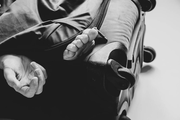Женская рука и нога торчат из чемодана, торговля людьми, работорговля, перевозка людей для продажи органов - Фото, изображение