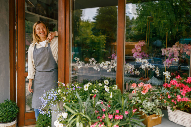 Kobieta kwiaciarnia mały właściciel firmy stojący w kwiaciarni. Wysokiej jakości zdjęcie - Zdjęcie, obraz