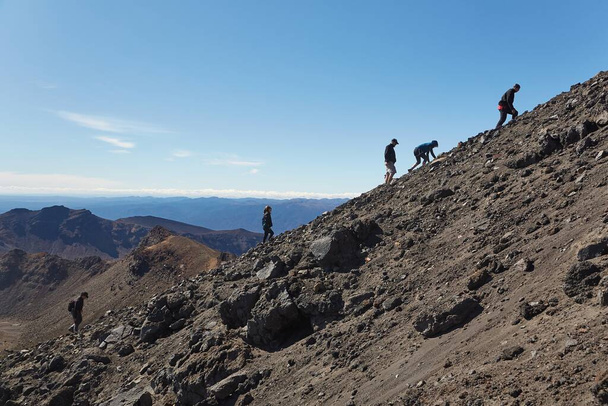 Tongariro Alpine Crossing, New Zealand - April 02, 2016: Tourist ascending the steep rough slope of mount Ngauruhoe, famous volcano uset as Mount Doom in the Lord of The Rings movies - Foto, Imagem