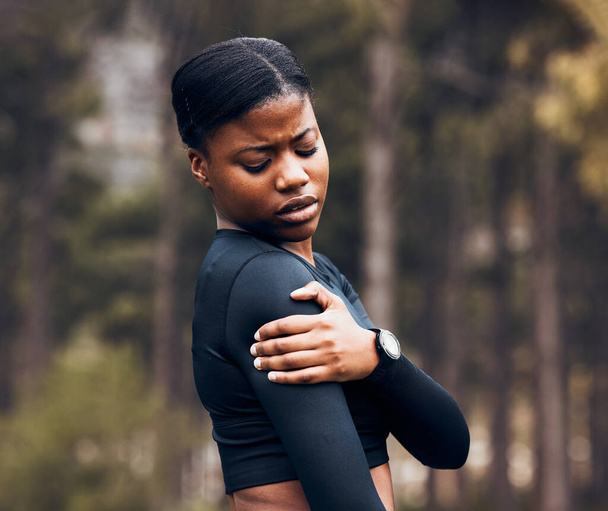 Shoulder, pain and sports woman outdoor for health risk, bruise and hands on wound in park. Fitness, black female athlete and arm injury of muscle, joint problem and first aid for exercise accident. - Photo, Image