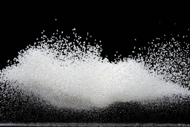 Czysta, wyrafinowana, latająca eksplozja kostki cukru, biały kryształowy cukier, abstrakcyjna mucha chmur. Czyste, rafinowane kostki cukru zatrzymują się w powietrzu, projektują obiekty spożywcze. Czarne tło odizolowane selektywne ostrość rozmycie - Zdjęcie, obraz