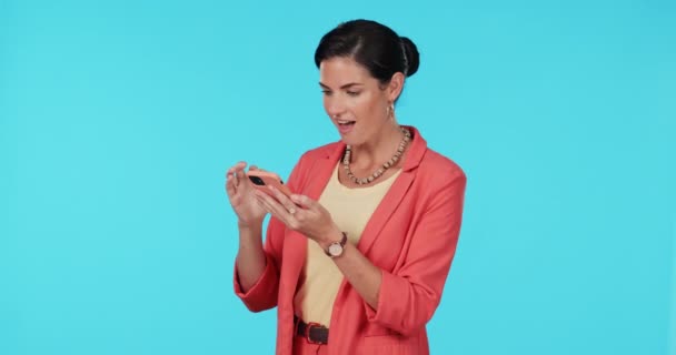 Woman, fist and phone in studio with wow, success or profit on fintech app, bonus or prize by blue background. Entrepreneur lady, cellphone and happy winner with shout, investment or lotto promotion. - Footage, Video
