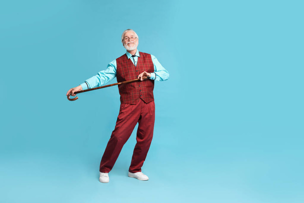 Cheerful senior man with walking cane on light blue background - 写真・画像
