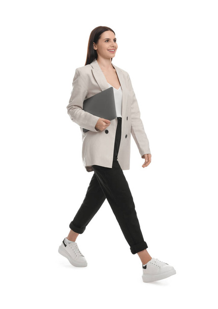 Beautiful businesswoman in suit with laptop walking on white background - Foto, afbeelding