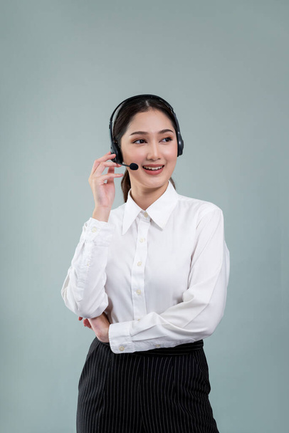 Ελκυστική Ασιάτισσα τηλεφωνήτρια με χαρούμενο χαμόγελο διαφημίζει ευκαιρίες εργασίας σε κενό χώρο, φορώντας επίσημο κοστούμι και ακουστικά σε παραμετροποιήσιμο απομονωμένο φόντο. Ενθουσιαστικός - Φωτογραφία, εικόνα