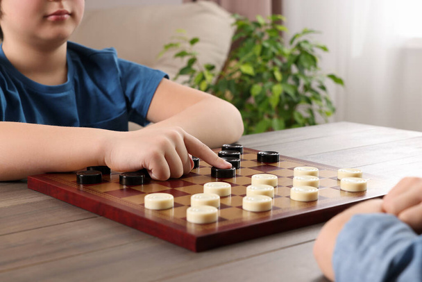 Children playing checkers at table in room, closeup - Foto, Imagem