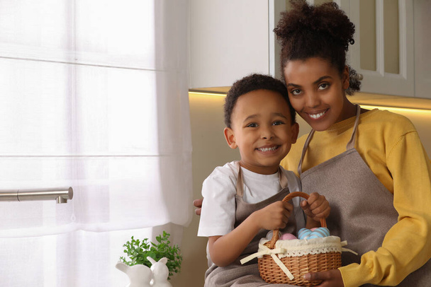 Happy African American mother and her cute son with Easter eggs in kitchen - Foto, Imagem
