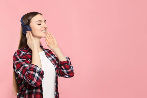 Happy woman in headphones enjoying music on pink background, space for text - Zdjęcie, obraz