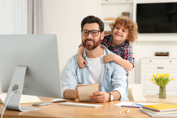Man working remotely at home. Father with his child at desk - Foto, Imagen