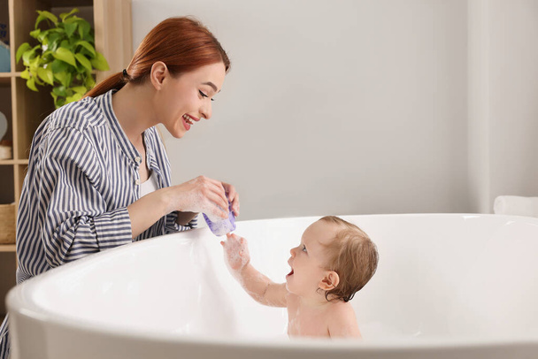Mother washing her little baby in tub at home - Foto, Imagen