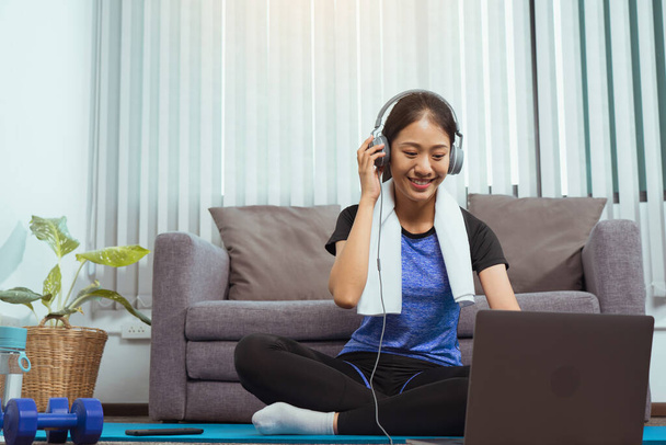 Asian beautiful young woman using laptop and headphones listen music while practicing exercise yoga at home. - Photo, image