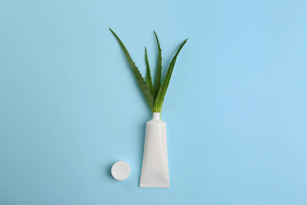 Tube of toothpaste and fresh aloe on light blue background, flat lay - 写真・画像