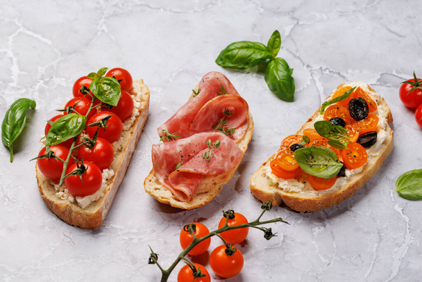 Um delicioso conjunto de sanduíches de bruschetta adornado com tomates suculentos, queijo e presunto salgado - Foto, Imagem