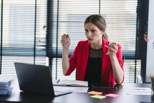 Eine gestresste und frustrierte Geschäftsfrau sitzt an ihrem Schreibtisch und schreit wütend auf ihren Laptop wegen eines Fehlers oder einer Krise im Geschäft. - Foto, Bild
