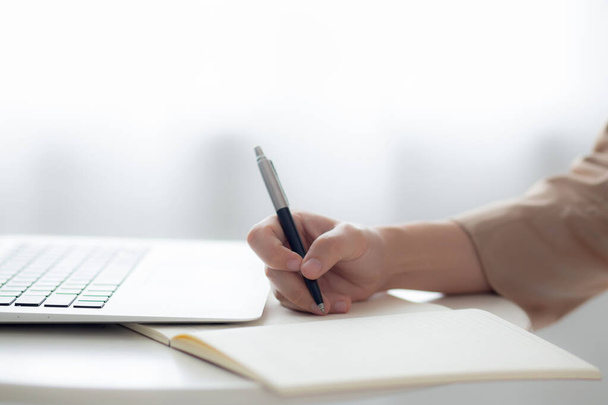 Detailní záběr ruce mladá asijská žena psaní na notebook pro plánování práce a používání notebooku na stole doma, ženské poznámky o financích, ženské studium, obchodní a komunikační koncept. - Fotografie, Obrázek