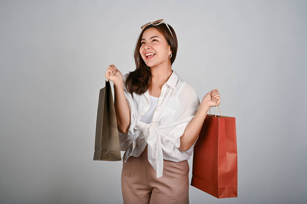 Nuori houkutteleva ja hymyilevä aasialainen nainen tilalla ostoskassit, ostoksia käsite. valkoinen eristetty tausta.  - Valokuva, kuva