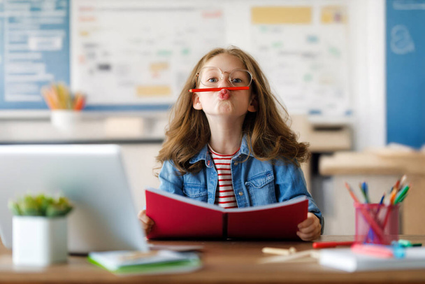 Back to school. Happy child is sitting at desk. Girl doing homework or online education. - Fotografie, Obrázek