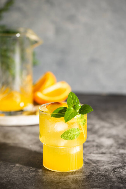 Lemonade or mojito cocktail with fruits and basil. Lemon and orange cold summer drink on grey table - Φωτογραφία, εικόνα