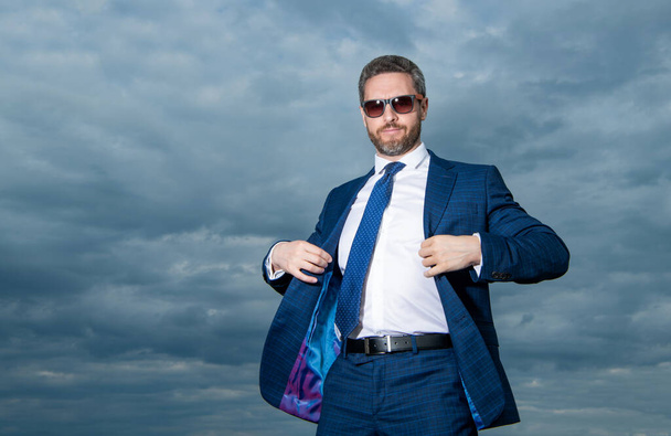 carefree business man in suit on sky background with copy space. carefree business man in suit outdoor. carefree business man in suit. photo of carefree business man in suit. - Zdjęcie, obraz