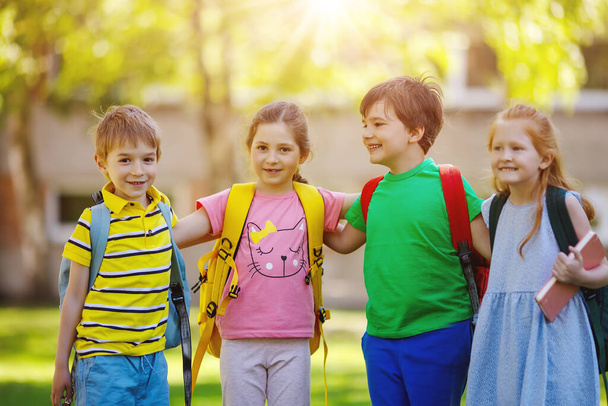 Group of children standing with backpacks near the school. Concept of the back to school and friendship. - Photo, Image