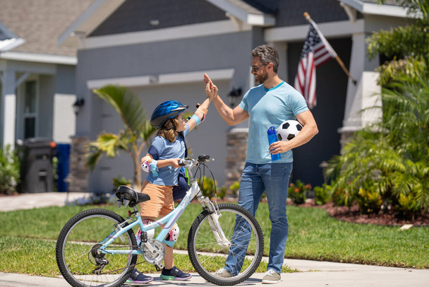 dad and son enjoying a ride together. Supportive father guiding son kid first bike ride. Father and son sharing biking adventure. father and son navigate the path together. creating memories. - Foto, imagen