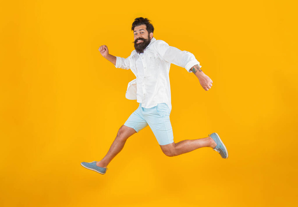 surprised bearded guy hurry on background. photo of bearded guy in a hurry wearing summer fashion. bearded guy in hurry isolated on yellow. bearded guy in hurry at studio. - Foto, afbeelding
