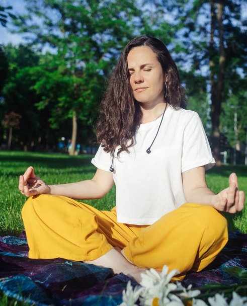 Сольная йога в парке. Женщина занимается медитацией в позе лотоса. Расслабление нервной системы. Самопомощь в разгрузке нервной системы. Спокойствие и восстановление - Фото, изображение
