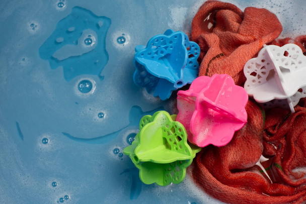 Bolas de lavandaria, Multi-cores Em um balde com lavanderia pronta para lavar, há água e uma pequena quantidade de bolhas de detergente - Foto, Imagem