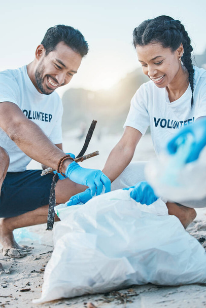 Волонтёр, мужчина и женщина убирают пляж для Всемирного дня Земли, заботятся и проявляют доброту к природе и окружающей среде. Помощь, переработка и счастливые люди в ngo собирать пластиковые отходы и загрязнение от океанского песка - Фото, изображение