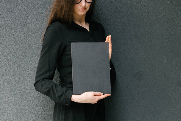 Black book cover in woman's hands. Book cover for mock up - 写真・画像
