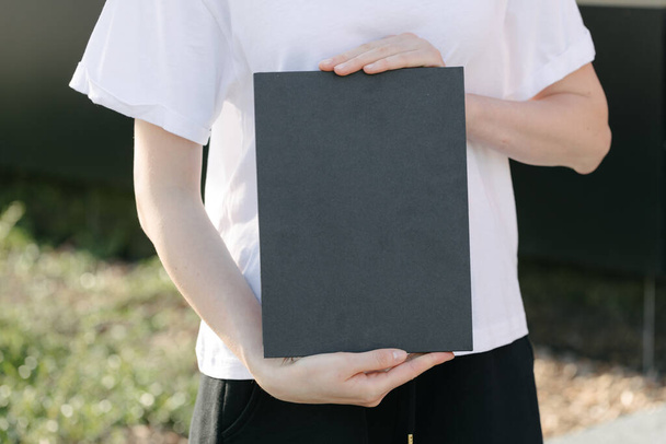 Black book cover in woman's hands. Book cover for mock up - Foto, Bild