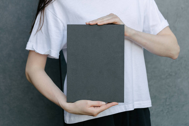 Black book cover in woman's hands. Book cover for mock up - Fotoğraf, Görsel