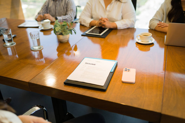 Κλείσιμο του βιογραφικού σημειώματος επί τάπητος υποψηφίου με τους εκπροσώπους του ΥΕ να κάθονται στο τραπέζι κατά τη διάρκεια συνέντευξης εργασίας στο γραφείο - Φωτογραφία, εικόνα