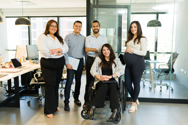 Portret van een groep multiraciale zakenmensen met een gehandicapte manager die in een modern kantoor op een rolstoel zit - Foto, afbeelding