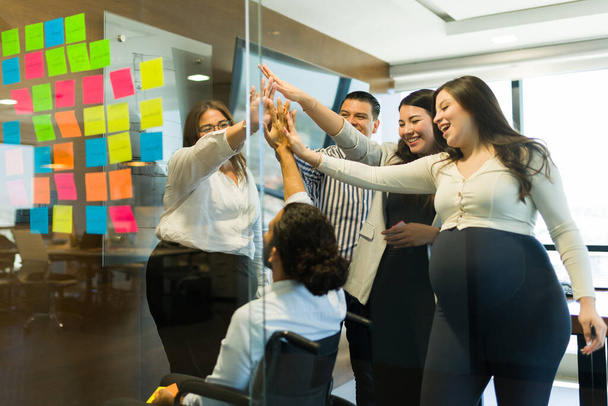 Grupo de profesionales de negocios masculinos y femeninos que ponen manos juntas después de una exitosa reunión de lluvia de ideas en la oficina - Foto, Imagen