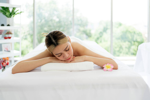 Beyaz çarşaflı ve sağlık merkezli Asya lüks spa salonundaki masaj yataklarına uzanmış genç bir kadın terapistten masaj bekliyor. Spa salonu konsepti - Fotoğraf, Görsel