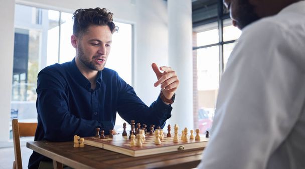 Board game, chess and men playing at a table while talking strategy or plan. Business partners or friends together to play, relax and bond with wooden icon for problem solving, challenge or checkmate. - Foto, Bild