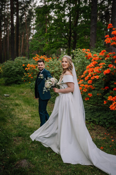 Bride and groom. The bride is dressed in a long very beautiful wedding dress, holding a bouquet of flowers - Fotó, kép